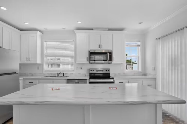 White kitchen with marble-topped island, white cabinetry, and stainless steel appliances.