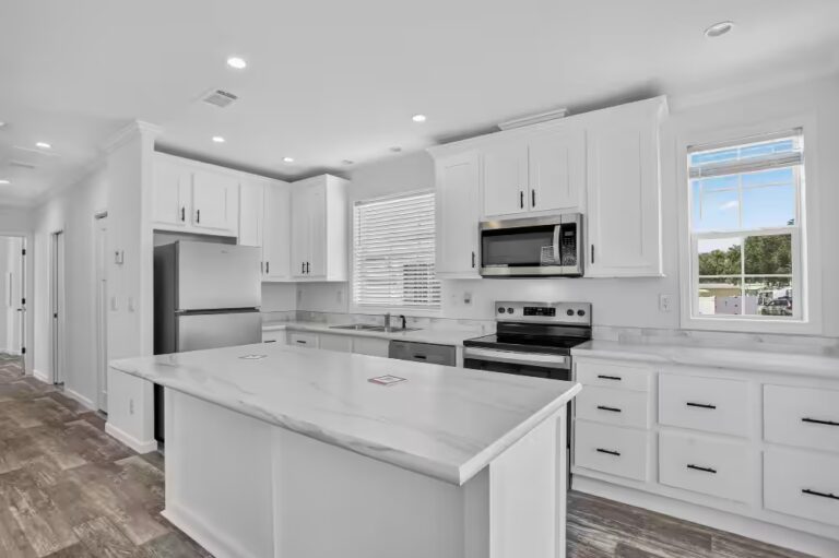 Bright white kitchen with marble island, stainless steel appliances, and white cabinets