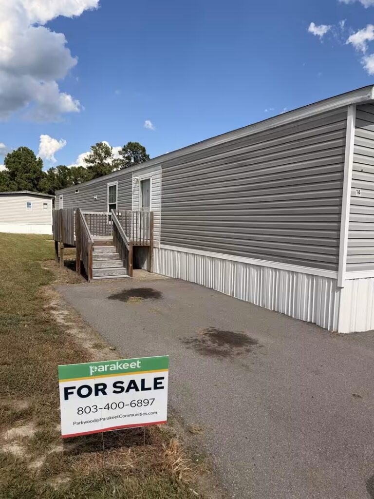 For Sale sign: parakeet, 803-400-6897, in front of gray manufactured home