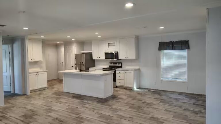Bright open kitchen with white cabinets, center island, stainless appliances, and wood-look flooring.