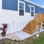 Blue and white house exterior with wooden staircase and railing leading to entrance door