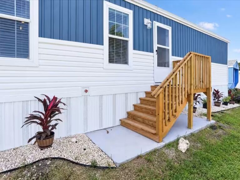 Blue and white house exterior with wooden staircase and railing leading to entrance door