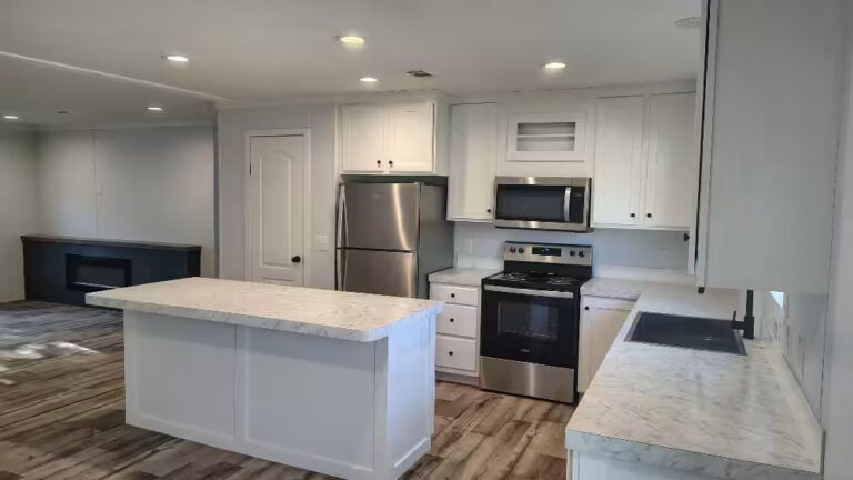 White kitchen with marble countertops, stainless steel appliances, and large center island.